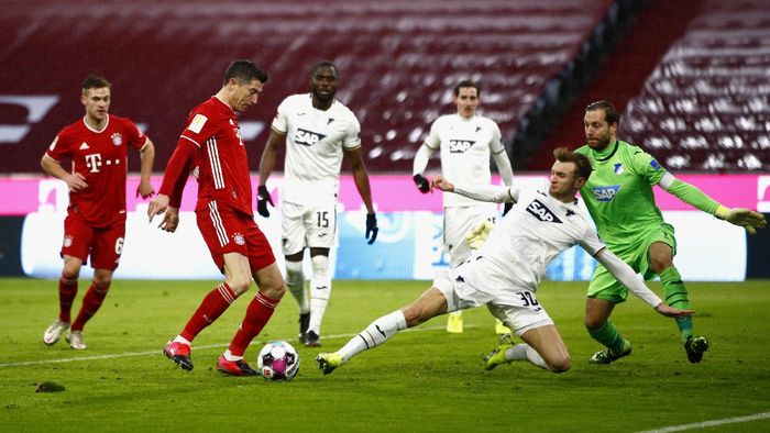 Bundesliga MUNICH, GERMANY - JANUARY 30: Robert Lewandowski of FC Bayern Munich scores his teams third goal past Oliver Baumann of TSG 1899 Hoffenheim during the Bundesliga match between FC Bayern Muenchen and TSG Hoffenheim at Allianz Arena on January 30, 2021 in Munich, Germany. Sporting stadiums around Germany remain under strict restrictions due to the Coronavirus Pandemic as Government social distancing laws prohibit fans inside venues resulting in games being played behind closed doors. (Photo by Adam Pretty/Getty Images)
