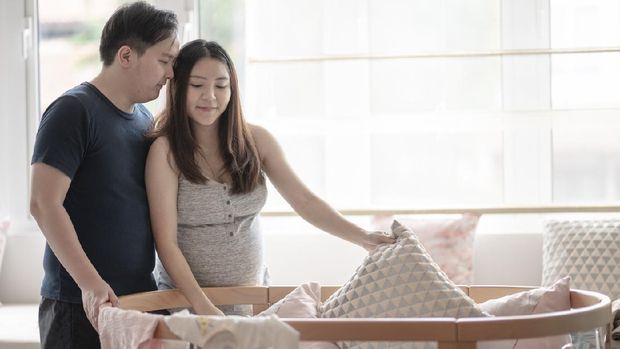 asia chinese pregnant woman getting ready for her new born baby preparing baby cloth and baby room with her husband