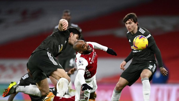 Manchester Uniteds Harry Maguire, left, duels for the ball with Arsenals Alexandre Lacazette, centre, during the English Premier League soccer match between Arsenal and Manchester United at the Emirates stadium in London, Saturday, Jan. 30, 2021. (Shaun Botterill/Pool via AP)