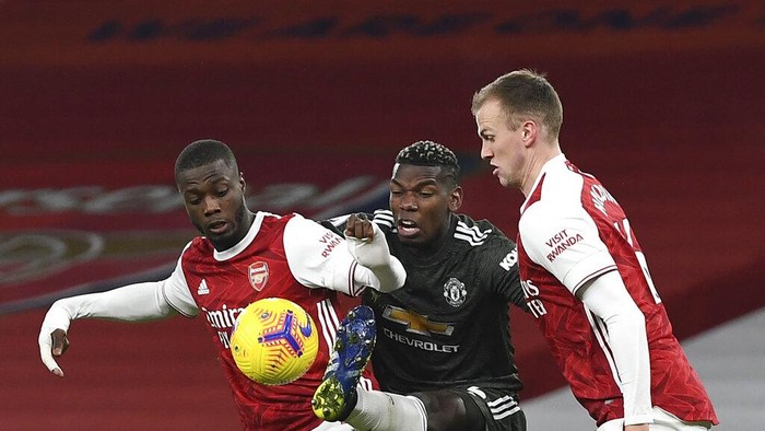 Arsenals Nicolas Pepe, left, duels for the ball with Manchester Uniteds Paul Pogba, centre, during the English Premier League soccer match between Arsenal and Manchester United at the Emirates stadium in London, Saturday, Jan. 30, 2021. (Andy Rain/Pool via AP)