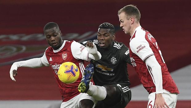 Arsenal's Nicolas Pepe, left, duels for the ball with Manchester United's Paul Pogba, centre, during the English Premier League soccer match between Arsenal and Manchester United at the Emirates stadium in London, Saturday, Jan. 30, 2021. (Andy Rain/Pool via AP)