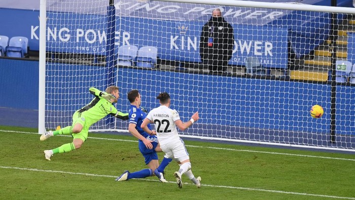 LEICESTER, ENGLAND - JANUARY 31: Jack Harrison of Leeds United scores their sides third goal past Kasper Schmeichel of Leicester City whilst under pressure from Johnny Evans of Leicester City during the Premier League match between Leicester City and Leeds United at The King Power Stadium on January 31, 2021 in Leicester, England. Sporting stadiums around the UK remain under strict restrictions due to the Coronavirus Pandemic as Government social distancing laws prohibit fans inside venues resulting in games being played behind closed doors. (Photo by Michael Regan/Getty Images)