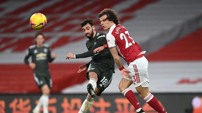 LONDON, ENGLAND - JANUARY 30: Bruno Fernandes of Manchester United takes a shot while under pressure from David Luiz of Arsenal during the Premier League match between Arsenal and Manchester United at Emirates Stadium on January 30, 2021 in London, England. Sporting stadiums around the UK remain under strict restrictions due to the Coronavirus Pandemic as Government social distancing laws prohibit fans inside venues resulting in games being played behind closed doors. (Photo by Shaun Botterill/Getty Images)