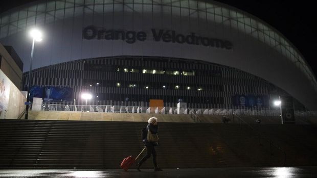 A woman walks by the velodrome stadium in Marseille, southern France, Saturday Jan. 30, 2021.The French league postponed Marseille's home game against Rennes just three hours before kickoff on Saturday after angry Marseille fans marched to the club's training complex to protest poor results. (AP Photo/Daniel Cole)
