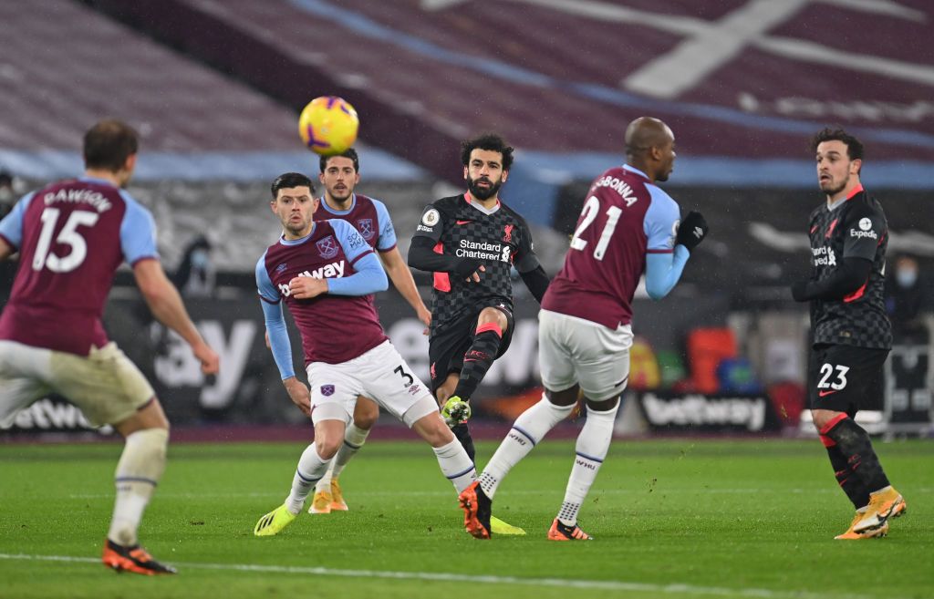 LONDON, ENGLAND - JANUARY 31: Mohamed Salah of Liverpool scores their side's first goal whilst under pressure from Aaron Cresswell of West Ham United during the Premier League match between West Ham United and Liverpool at London Stadium on January 31, 2021 in London, England. Sporting stadiums around the UK remain under strict restrictions due to the Coronavirus Pandemic as Government social distancing laws prohibit fans inside venues resulting in games being played behind closed doors. (Photo by Justin Setterfield/Getty Images)