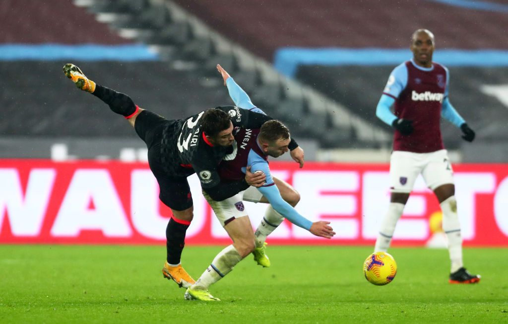 LONDON, ENGLAND - JANUARY 31: Mohamed Salah of Liverpool scores their side's first goal whilst under pressure from Aaron Cresswell of West Ham United during the Premier League match between West Ham United and Liverpool at London Stadium on January 31, 2021 in London, England. Sporting stadiums around the UK remain under strict restrictions due to the Coronavirus Pandemic as Government social distancing laws prohibit fans inside venues resulting in games being played behind closed doors. (Photo by Justin Setterfield/Getty Images)