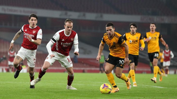 LONDON, ENGLAND - NOVEMBER 29: Daniel Podence of Wolverhampton Wanderers beats Hector Bellerin and Rob Holding of Arsenal during the Premier League match between Arsenal and Wolverhampton Wanderers at Emirates Stadium on November 29, 2020 in London, England. Sporting stadiums around the UK remain under strict restrictions due to the Coronavirus Pandemic as Government social distancing laws prohibit fans inside venues resulting in games being played behind closed doors. (Photo by Catherine Ivill/Getty Images)