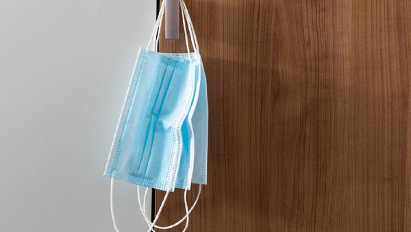 Couple of used face masks hanging on the wall. People tend to wear same protective mask more than once. Covid-19 concept.