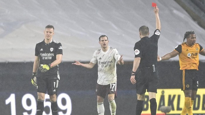 Arsenals goalkeeper Bernd Leno, left, is shown a red card during the English Premier League match between Wolverhampton Wanderers and Arsenal at the Molineux Stadium in Wolverhampton, England, Tuesday, Feb. 2, 2021. (Shaun Botterill/Pool via AP)