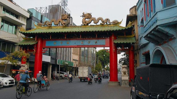 Surabaya, Indonesia - October 24, 2013: Kya-Kya (walk street) in Chinatown Surabaya. Cyclists and a truck riding onto the chinese Gate.