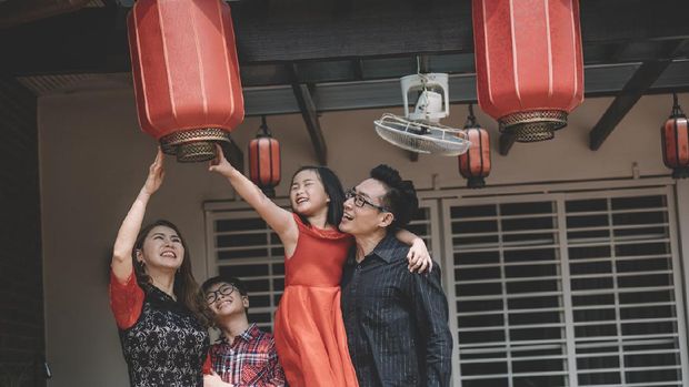 an asian chinese family in malaysia fixing their red lanterns for chinese new year preparation in front of their house