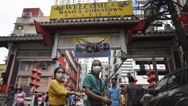 This photo taken on February 14, 2020 shows people wearing face masks walking in front of an altar in the Binondo district of Chinatown in Manila. - Bustling century-old Chinatowns from Melbourne to San Francisco have fallen quiet and businesses are struggling to survive as fears over the deadly novel coronavirus outbreak ripple around the world. (Photo by Ted ALJIBE / AFP) / TO GO WITH Australia-China-virus-health-economy,FOCUS by Sean GLEESON