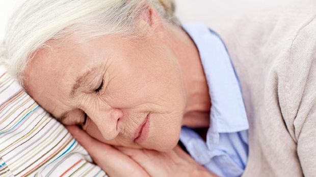 age, relax and people concept - happy senior woman sleeping on pillow at home
