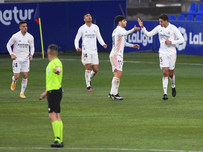 HUESCA, SPAIN - FEBRUARY 06: Raphael Varane of Real Madrid celebrates with team mate Marco Asensio after scoring their side's  first goal during the La Liga Santander match between SD Huesca and Real Madrid at Estadio El Alcoraz on February 06, 2021 in Huesca, Spain. Sporting stadiums around Spain remain under strict restrictions due to the Coronavirus Pandemic as Government social distancing laws prohibit fans inside venues resulting in games being played behind closed doors. (Photo by Alex Caparros/Getty Images)