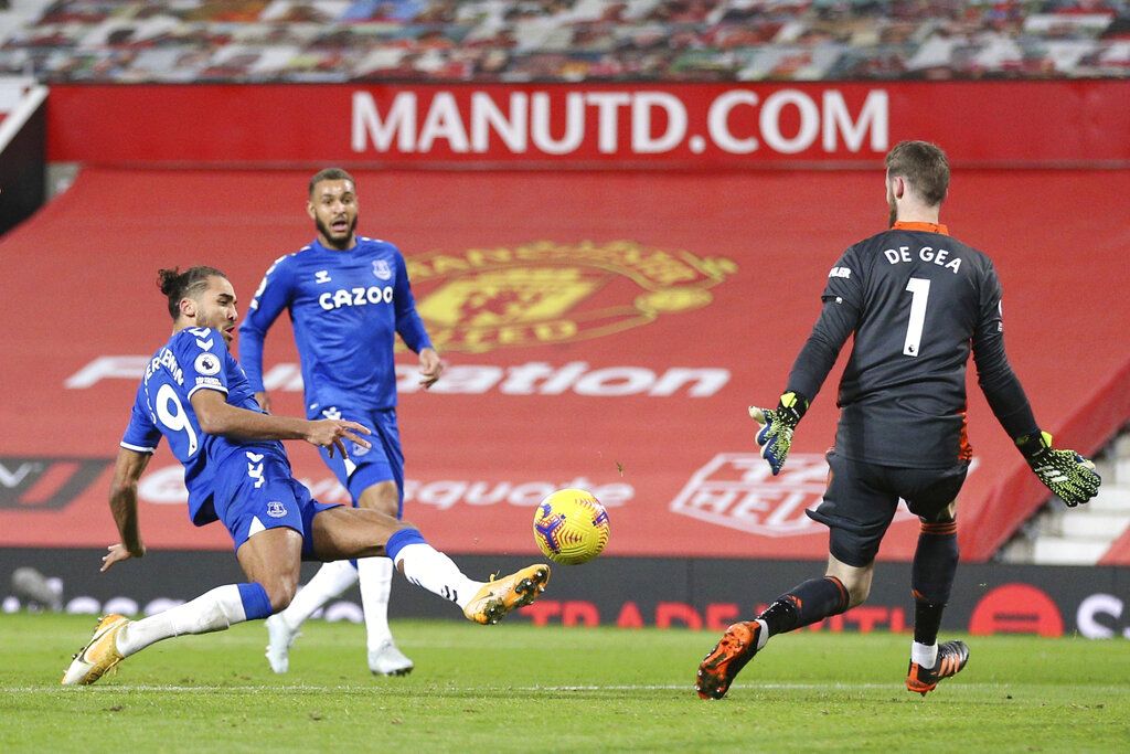 Everton's Dominic Calvert-Lewin, left, scores his side's third goal during an English Premier League soccer match between Manchester United and Everton at the Old Trafford stadium in Manchester, England, Saturday Feb. 6, 2021. (Alex Pantling/Pool via AP)