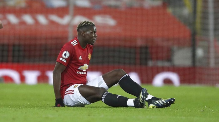 Manchester Uniteds Paul Pogba sits on the ground after getting injured during an English Premier League soccer match between Manchester United and Everton at the Old Trafford stadium in Manchester, England, Saturday Feb. 6, 2021. (Martin Rickett/Pool via AP)