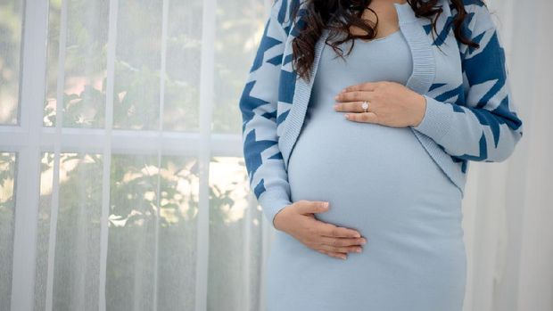 Beautiful young women in the third trimester of pregnancy Pregnant woman holding arms in her stomach Expecting child concepts White background