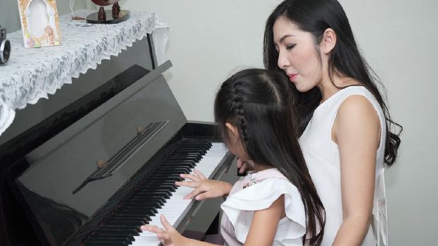 Strict musician mother is teaching her daughter to play the piano. Musical recreation activities for children.