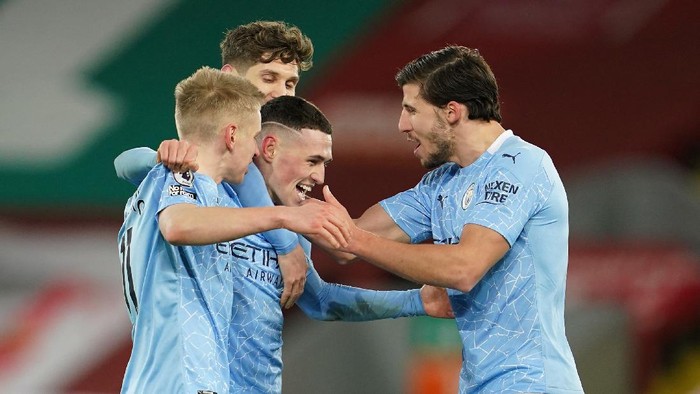 LIVERPOOL, ENGLAND - FEBRUARY 07: Phil Foden of Manchester City celebrates with team mates (L - R) Oleksandr Zinchenko, and Ruben Dias after scoring their sides fourth goal during the Premier League match between Liverpool and Manchester City at Anfield on February 07, 2021 in Liverpool, England. Sporting stadiums around the UK remain under strict restrictions due to the Coronavirus Pandemic as Government social distancing laws prohibit fans inside venues resulting in games being played behind closed doors (Photo by Jon Super - Pool/Getty Images)