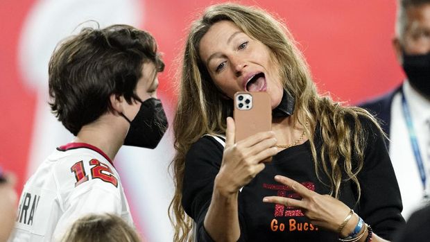 Wife of Tampa Bay Buccaneers quarterback Tom Brady, Gisele Bundchen looks at a phone with her son after the NFL Super Bowl 55 football game against the Kansas City Chiefs, Sunday, Feb. 7, 2021, in Tampa, Fla. The Buccaneers defeated the Chiefs 31-9 to win the Super Bowl. (AP Photo/Ashley Landis)