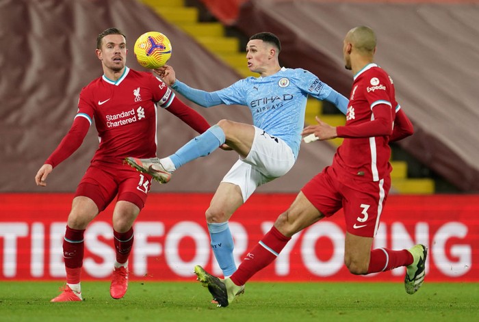 LIVERPOOL, ENGLAND - FEBRUARY 07: Phil Foden of Manchester City battles for possession with (L - R) Jordan Henderson and Fabinho of Liverpool during the Premier League match between Liverpool and Manchester City at Anfield on February 07, 2021 in Liverpool, England. Sporting stadiums around the UK remain under strict restrictions due to the Coronavirus Pandemic as Government social distancing laws prohibit fans inside venues resulting in games being played behind closed doors (Photo by Jon Super - Pool/Getty Images)