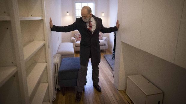 Estate agent David Myers leads a tour of what is dubbed 'London's thinnest house' in west London on February 5, 2021. - Wedged neatly between a doctor's surgery and a shuttered hairdressing salon, the five floor house in Shepherds Bush is just 5ft 6ins (1.6 metres) at its narrowest point and is currently on the market for £950,000 ($1,300,000, 1,100,000 euros). The unusual property, originally a Victorian hat shop with storage for merchandise and living quarters on its upper floors, was built sometime in the late 19th or early 20th century. (Photo by Tolga Akmen / AFP)