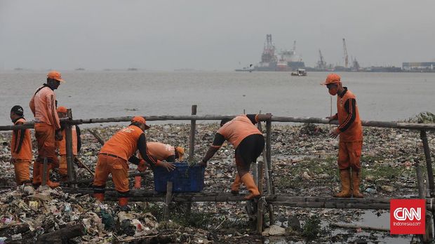 Pekerja Penanganan Sarana dan Prasarana Umum (PPSU) membersihkan sampah domestik di pesisir laut Marunda, Jakarta, Selasa, 9 Februari 2021. Sampah yang terbawa arus laut mengakibatkan tumpukan di pinggir laut. CNNIndonesia/Safir Makki