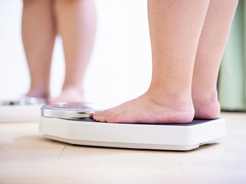 plus size asian girl look mirror and measure her weight by scale