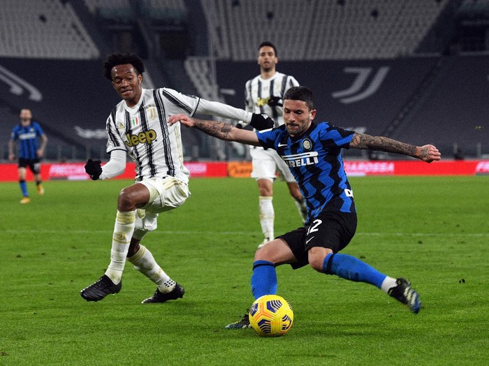 TURIN, ITALY - FEBRUARY 09: Stefano Sensi of FC Internazionale is closed down by Juan Cuadrado of Juventus during the Coppa Italia semi-final Juventus and FC Internazionale at Allianz Stadium on February 09, 2021 in Turin, Italy. Sporting stadiums around Italy remain under strict restrictions due to the Coronavirus Pandemic as Government social distancing laws prohibit fans inside venues resulting in games being played behind closed doors. (Photo by Chris Ricco/Getty Images)