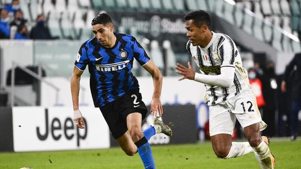 Inter's Achraf Hakimi, left, dribbles as Juventus' Alex Sandro chases during the Italian Cup, return-leg, semifinal soccer match between Juventus and Inter Milan, at the Turin Allianz Stadium, Italy, Tuesday, Feb. 9, 2021. (Marco Alpozzi/LaPresse via AP)