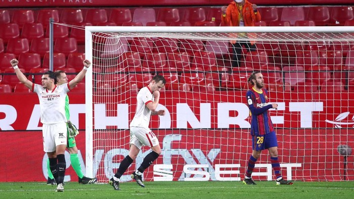 SEVILLE, SPAIN - FEBRUARY 10: Ivan Rakitic (C) of Sevilla celebrates after scoring their sides second goal as Oscar Mingueza of FC Barcelona looks on during the Copa del Rey Semi Final First Leg match between Sevilla and FC Barcelona at Estadio Ramon Sanchez Pizjuan on February 10, 2021 in Seville, Spain. Sporting stadiums around Spain remain under strict restrictions due to the Coronavirus Pandemic as Government social distancing laws prohibit fans inside venues resulting in games being played behind closed doors. (Photo by Fran Santiago/Getty Images)