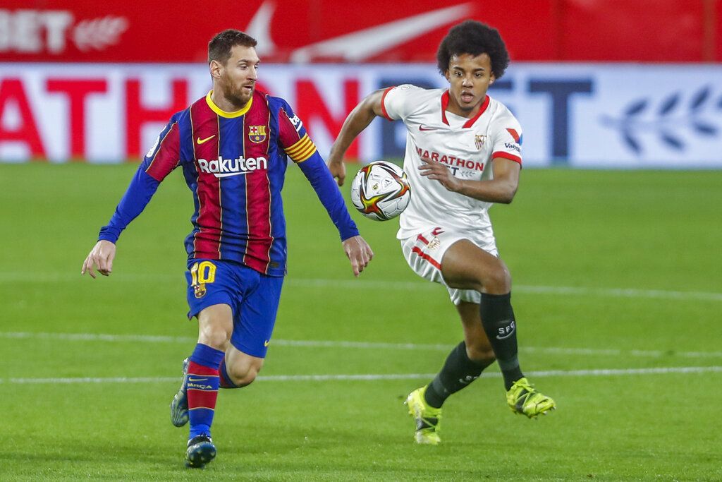 Barcelona's Lionel Messi, left, vies for the ball with Sevilla's Jules Kounde during a Spanish Copa del Rey semifinal soccer match between Sevilla and FC Barcelona at Ramon Sanchez Pizjuan stadium in Seville , Spain, Wednesday, Feb. 10, 2021. (AP Photo/Angel Fernandez)