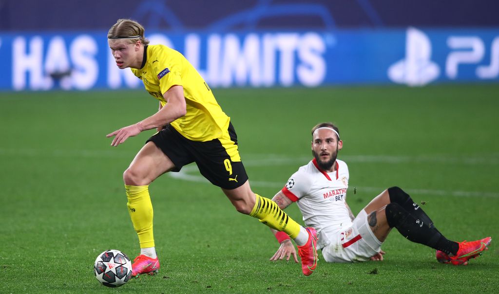 SEVILLE, SPAIN - FEBRUARY 17: Erling Haaland of Borussia Dortmund gets away from Nemanja Gudelj of Sevilla during the UEFA Champions League Round of 16 match between Sevilla FC and Borussia Dortmund at Estadio Ramon Sanchez Pizjuan on February 17, 2021 in Seville, Spain. Sporting stadiums around Spain remain under strict restrictions due to the Coronavirus Pandemic as Government social distancing laws prohibit fans inside venues resulting in games being played behind closed doors. (Photo by Fran Santiago/Getty Images)