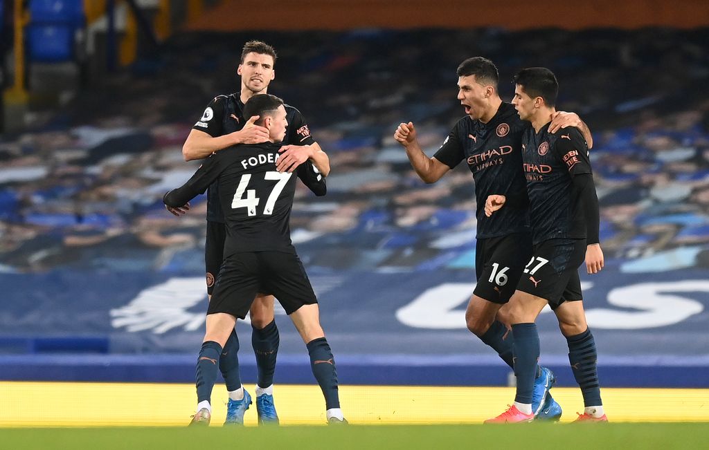 LIVERPOOL, ENGLAND - FEBRUARY 17: Phil Foden of Manchester City celebrates with teammates (L - R) Ruben Dias, Rodrigo and Joao Cancelo after scoring his team's first goal during the Premier League match between Everton and Manchester City at Goodison Park on February 17, 2021 in Liverpool, England.  Sports stadiums across the UK remain under strict restrictions due to the coronavirus pandemic, as the government's social distancing laws prohibit fans within venues, causing games to be played behind closed doors.  (Photo by Michael Regan / Getty Images)