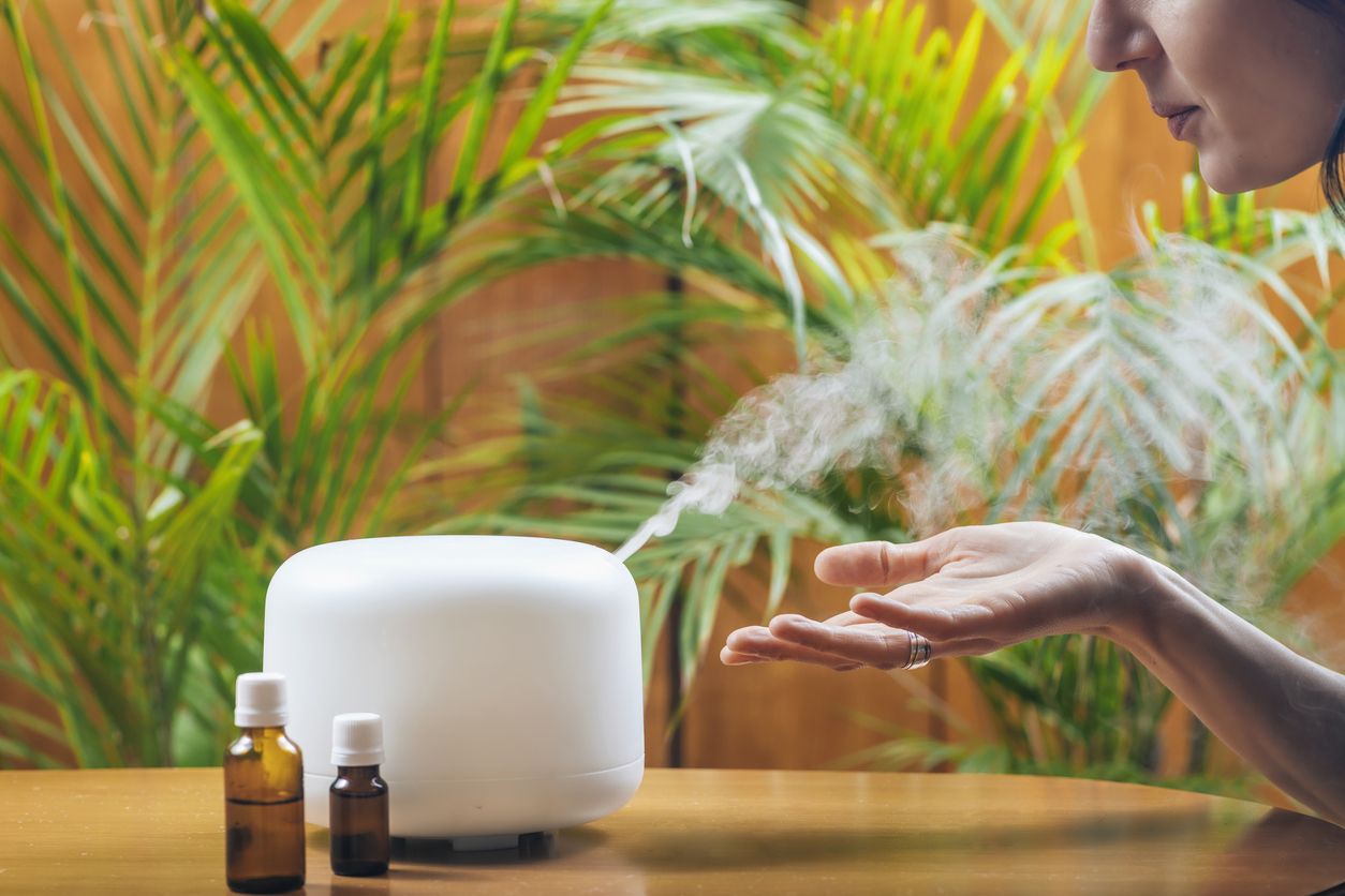 Woman Enjoying Aroma Therapy Steam Scent from Home Essential Oil Diffuser or Air Humidifier. Ultrasonic technology, increasing air humidity indoors for more comfortable living conditions