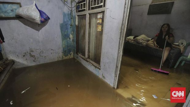 Warga berjalan melintasi banjir yang merendam kawasan  Pancoran Barat Jakarta, Jumat, 19 Februari 2021. Sejumlah kawasan di Jakarta terendam banjir akibat curah hujan yang tinggi.  CNN Indonesia/Adhi Wicaksono