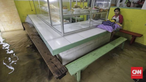 Warga berjalan melintasi banjir yang merendam kawasan  Pancoran Barat Jakarta, Jumat, 19 Februari 2021. Sejumlah kawasan di Jakarta terendam banjir akibat curah hujan yang tinggi. CNN Indonesia/Adhi Wicaksono