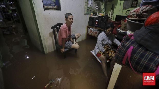 Warga berjalan melintasi banjir yang merendam kawasan  Pancoran Barat Jakarta, Jumat, 19 Februari 2021. Sejumlah kawasan di Jakarta terendam banjir akibat curah hujan yang tinggi. CNN Indonesia/Adhi Wicaksono