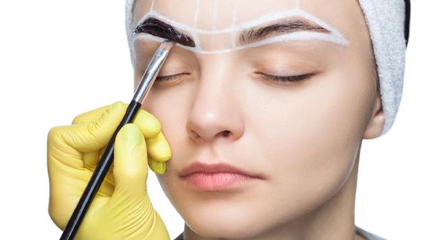 cetakan alis The make-up artist paints eyebrows with henna of a young girl. Beautiful thick eyebrows close up. Professional makeup and cosmetology skin care.