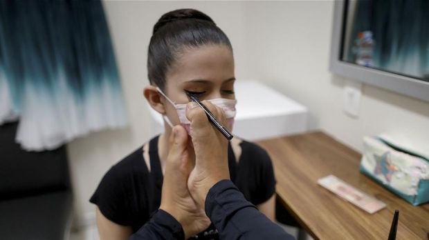 Vitoria Bueno, a 16-year-old dancer whose genetic condition left her without arms, uses her foot to apply makeup on a teammate from the Andrea Falsarella ballet academy on the backstage of the Inatel Theater in Santa Rita do Sapucai, Brazil, February 5, 2021. Picture taken February 5, 2021. REUTERS/Ueslei Marcelino     TPX IMAGES OF THE DAY