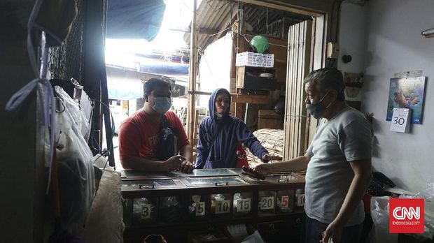 Tjan Kee Liong, kakak Tjan Kee Beng, saat melayani pembeli di toko mereka. Kebanyakan pelanggan lebih menyukai tembakau mole dan kretek.