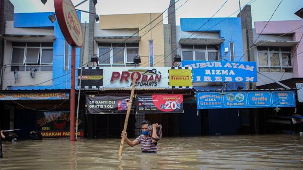 Warga berjalan menerobos banjir di kawasan Regency, Pasar Kemis, Kabupaten Tangerang, Banten, Sabtu (20/2/2021). Hujan deras yang mengguyur sejak Sabtu (20/2) dini hari menyebabkan kawasan tersebut terendam banjir hingga 1,5 meter. ANTARA FOTO/Fauzan/rwa.
