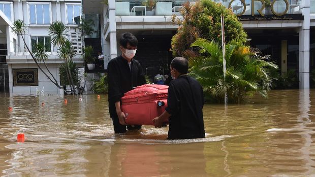 Petugas hotel membawa koper milik tamu saat banjir melanda kawasan Kemang, Jakarta Selatan, Sabtu (20/2/2021). Banjir yang terjadi akibat curah hujan tinggi serta drainase yang buruk membuat kawasan Kemang banjir setinggi 1,5 meter. ANTARA FOTO/Indrianto Eko Suwarso/rwa.