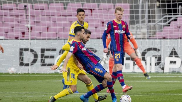 Barcelona's Sergio Busquets, center, controls the ball with Cadiz's Alberto Perea during the Spanish La Liga soccer match between FC Barcelona and Cadiz at the Camp Nou stadium in Barcelona, Spain, Sunday, Feb. 21, 2021. (AP Photo/Joan Monfort)