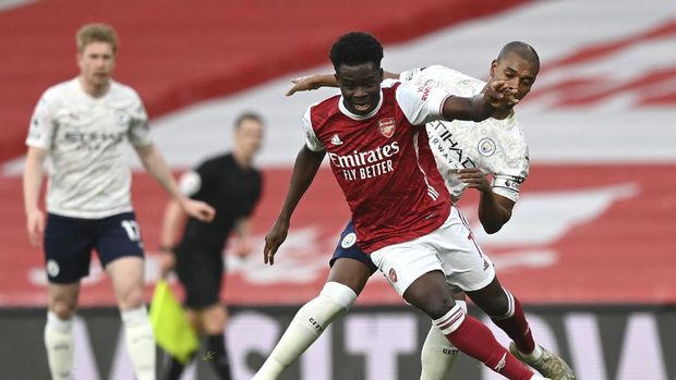 Arsenal's Bukayo Saka, left, and Manchester City's John Stones challenge for the ball during the English Premier League soccer match between Arsenal and Manchester City at the Emirates stadium in London, England, Sunday, Feb. 21, 2021. (Shaun Botterill/Pool via AP)