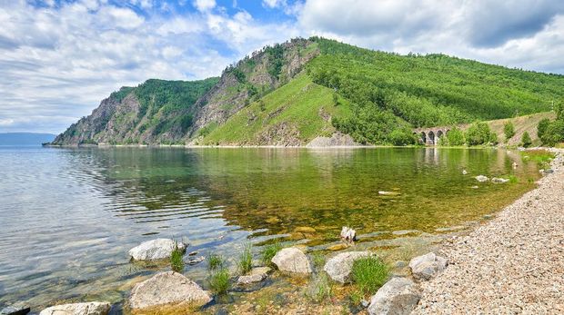Clear water in bay of Lake Baikal. Landscape with a stone arched viaduct of the Circum-Baikal Railway. Irkutsk region. Eastern Siberia
