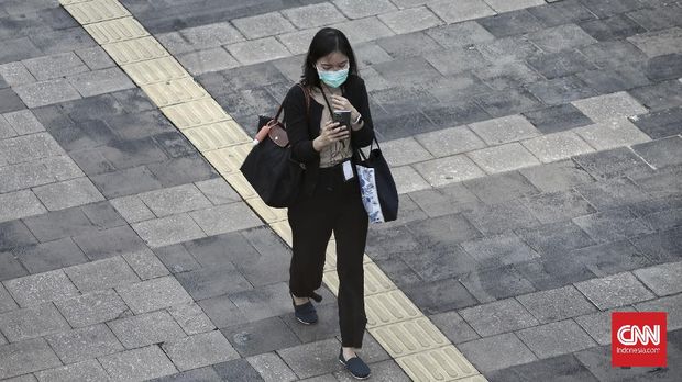 Pekerja melintas di Jalan Jenderal  Sudirman. Jakarta,  Senin (22/2/2021). Peraturan Pemerintah (PP) nomor 35 tahun 2021 yang ditandatangani Presiden Joko Widodo pada 2 Februari lalu memperbolehkan perusahaan untuk tidak membayar penuh pesangon karyawan yang terkena pemutusan hubungan kerja (PHK) dalam keadaan tertentu. CNN Indonesia/Andry Novelino