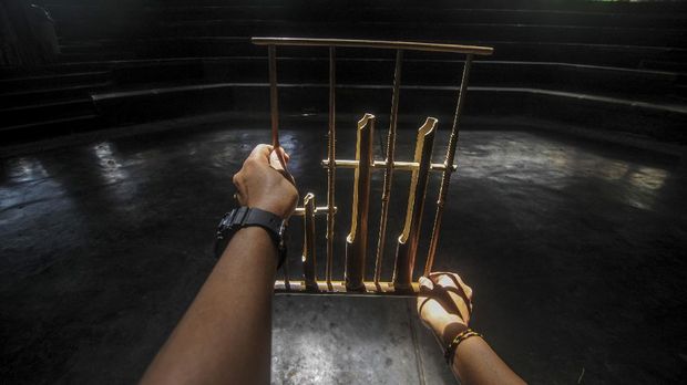 Seorang instruktur memegang angklung di aula pementasan yang kosong di Saung Angklung Udjo.