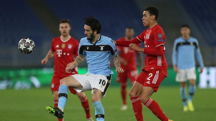 ROME, ITALY - FEBRUARY 23: Luis Alberto of S.S. Lazio battles for possession with Jamal Musiala of FC Bayern Muenchen during the UEFA Champions League Round of 16 match between Lazio Roma and Bayern München at Olimpico Stadium on February 23, 2021 in Rome, Italy. Sporting stadiums around Italy remain under strict restrictions due to the Coronavirus Pandemic as Government social distancing laws prohibit fans inside venues resulting in games being played behind closed doors. (Photo by Paolo Bruno/Getty Images)