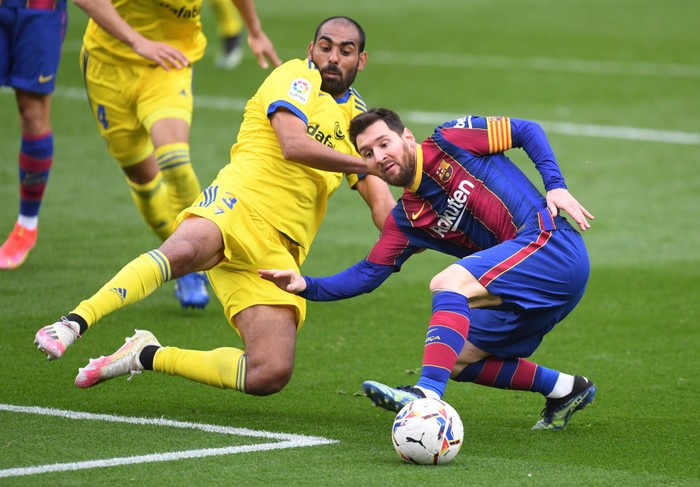 BARCELONA, SPAIN - FEBRUARY 21: Lionel Messi of FC Barcelona is challenged by Fali of Cadiz CF during the La Liga Santander match between FC Barcelona and Cadiz CF at Camp Nou on February 21, 2021 in Barcelona, Spain. Sporting stadiums around Spain remain under strict restrictions due to the Coronavirus Pandemic as Government social distancing laws prohibit fans inside venues resulting in games being played behind closed doors. (Photo by Alex Caparros/Getty Images)